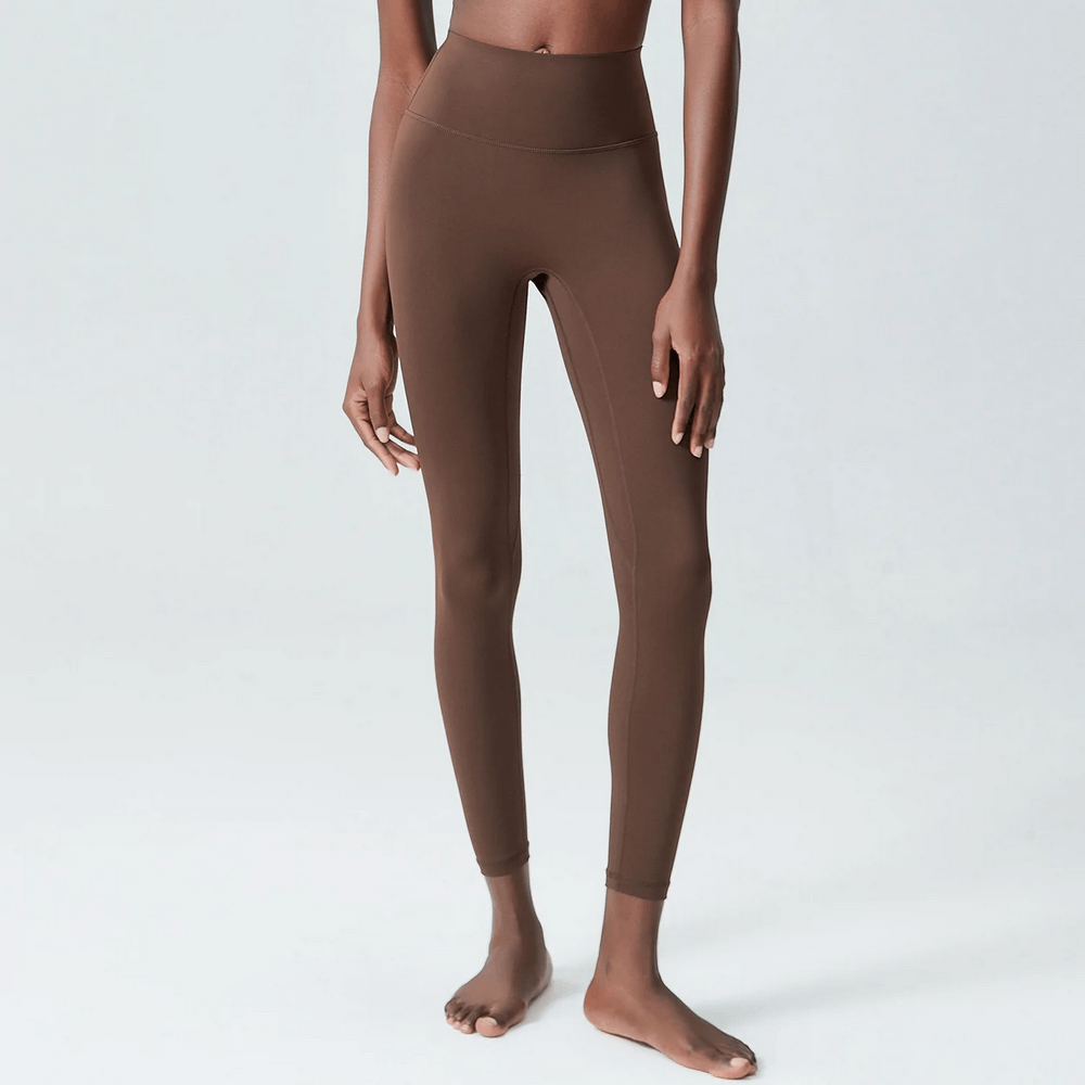 Model wearing brown ankle-length yoga leggings showcasing a snug fit and elastic waist, ideal for versatile workouts and active lifestyles.